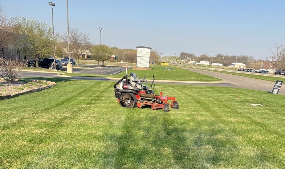 Zero-turn mower striping a large commercial lawn along a road frontage