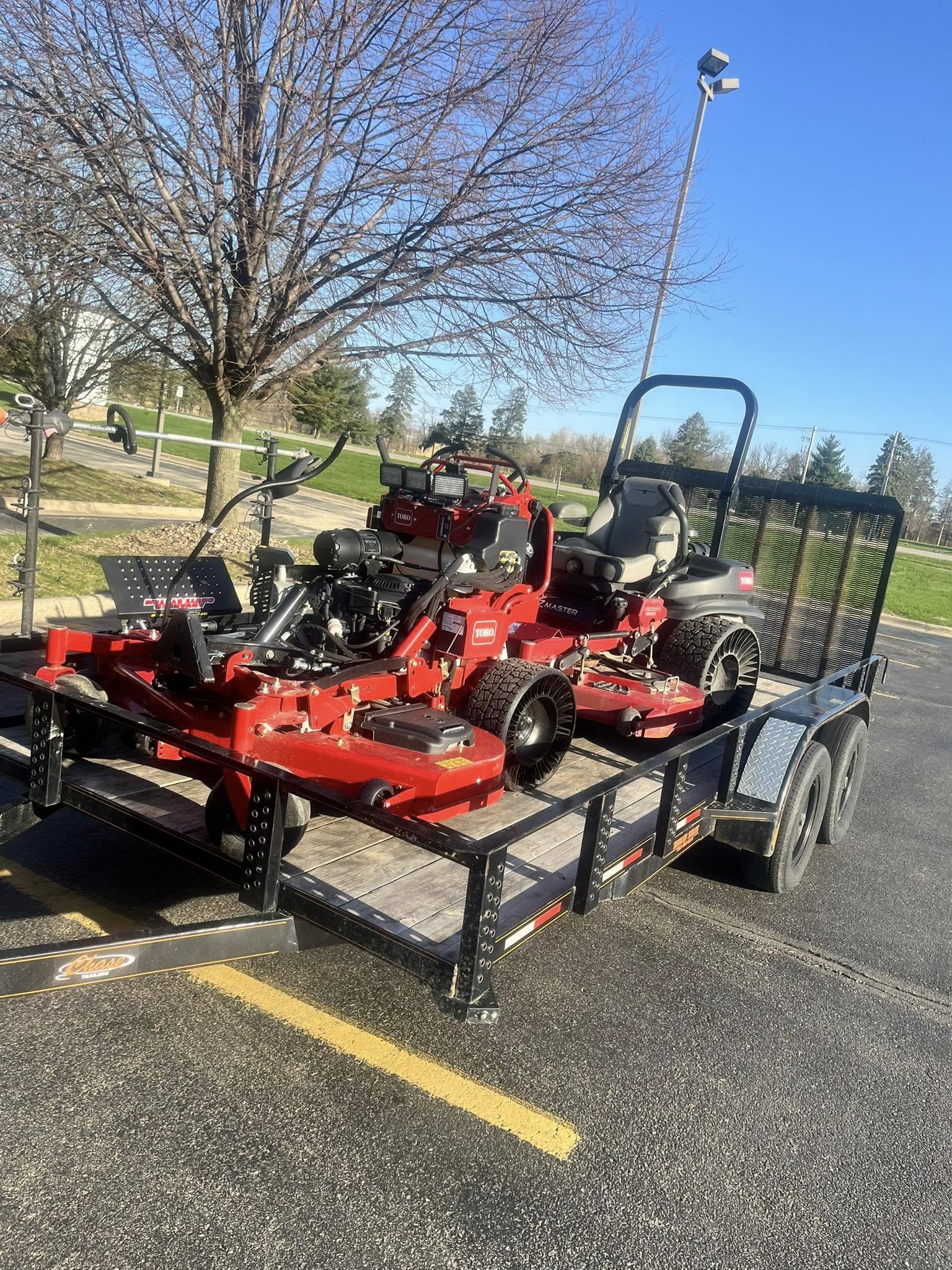 Toro stand-on and zero-turn mowers loaded on a trailer